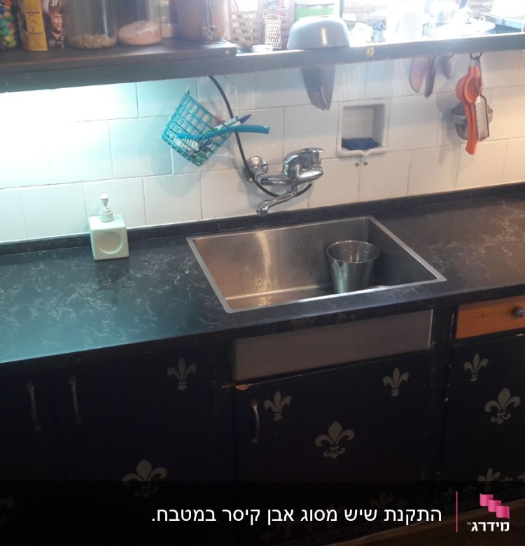 משטח שיש שחור עם כיור נירוסטה במטבח